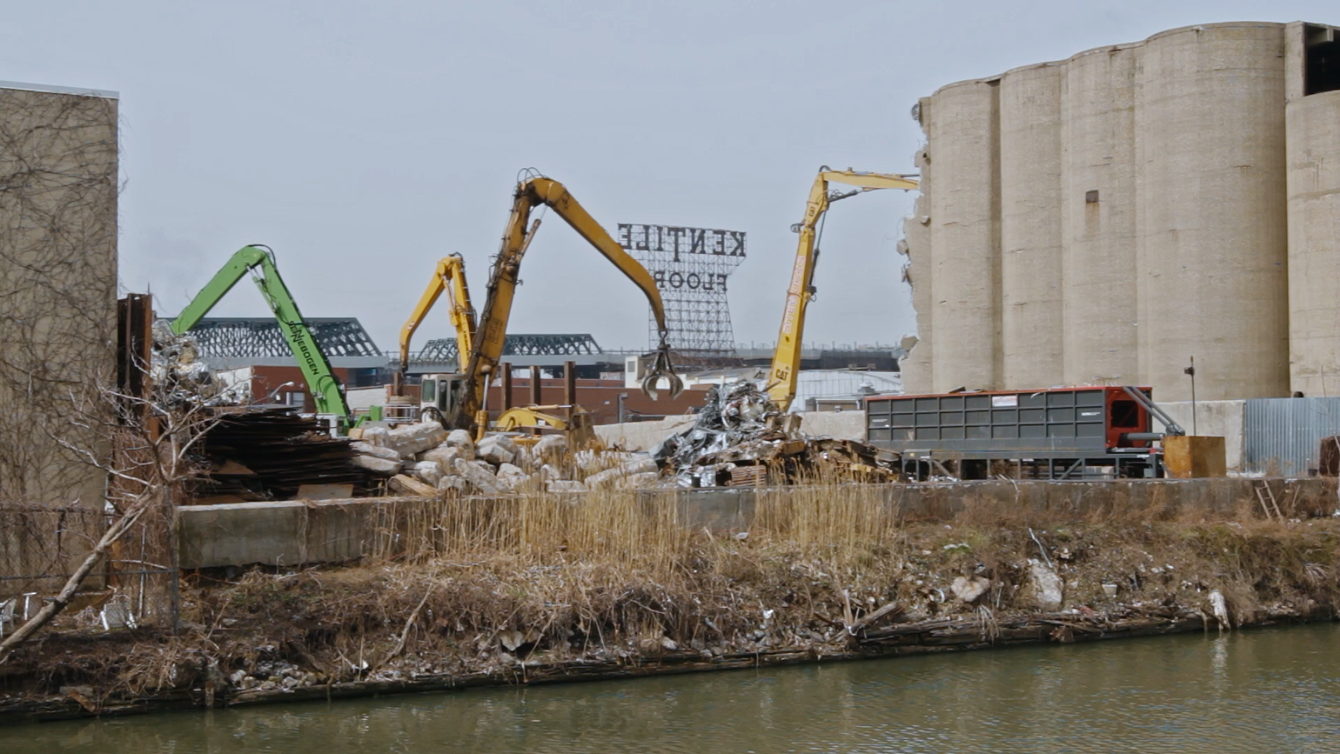 Excavators moving concrete in front of water 